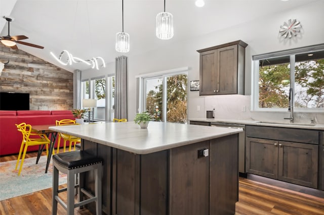 kitchen with ceiling fan, sink, vaulted ceiling, dark brown cabinets, and a kitchen island