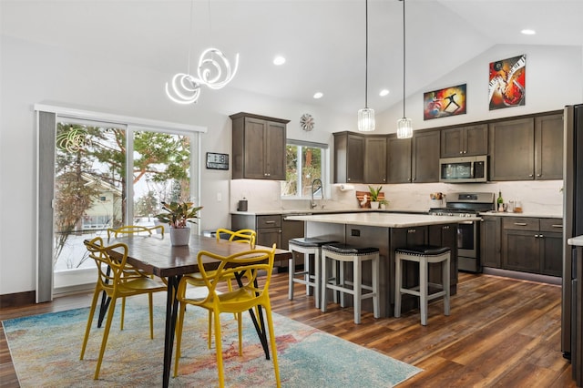 kitchen featuring tasteful backsplash, a kitchen island, stainless steel appliances, and lofted ceiling