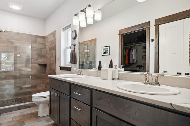 bathroom with hardwood / wood-style floors, vanity, toilet, and a shower with door