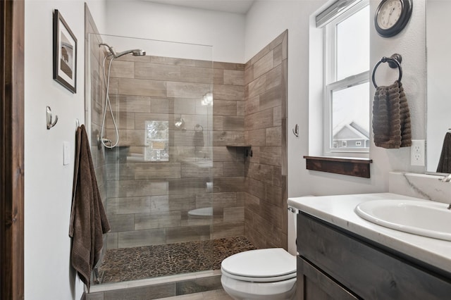 bathroom featuring vanity, toilet, and a tile shower