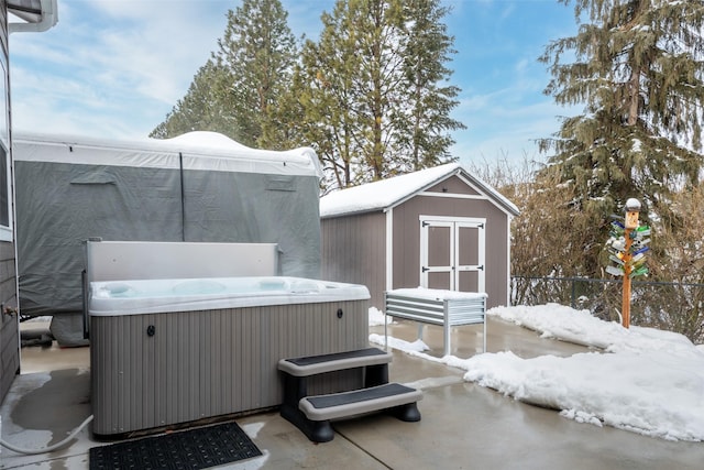 snow covered patio featuring a shed and a hot tub