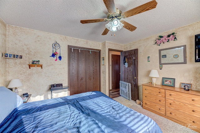 bedroom with light carpet, a closet, ceiling fan, a textured ceiling, and heating unit