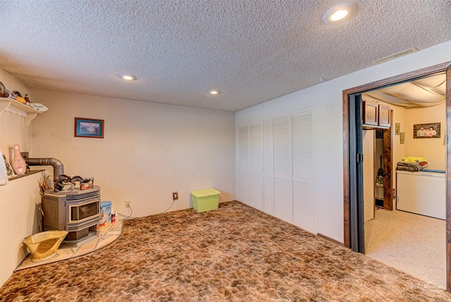 interior space with carpet flooring, a wood stove, and a textured ceiling