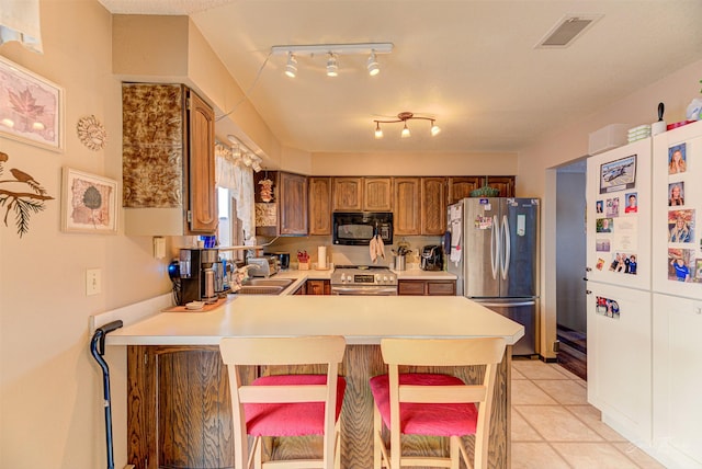 kitchen featuring kitchen peninsula, appliances with stainless steel finishes, sink, a breakfast bar area, and light tile patterned flooring