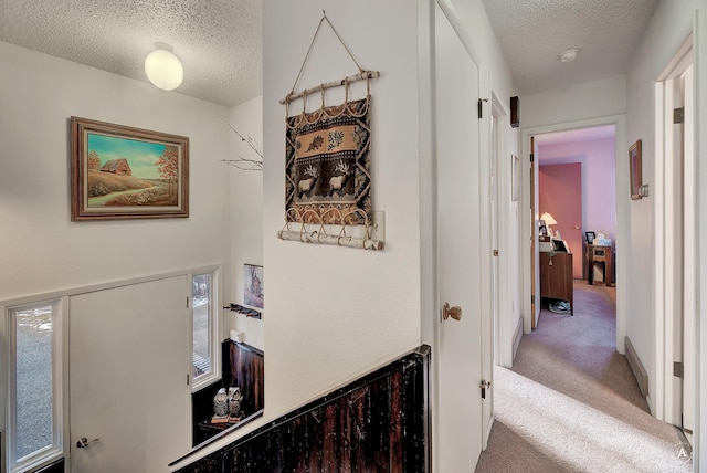 hall with a textured ceiling and carpet floors