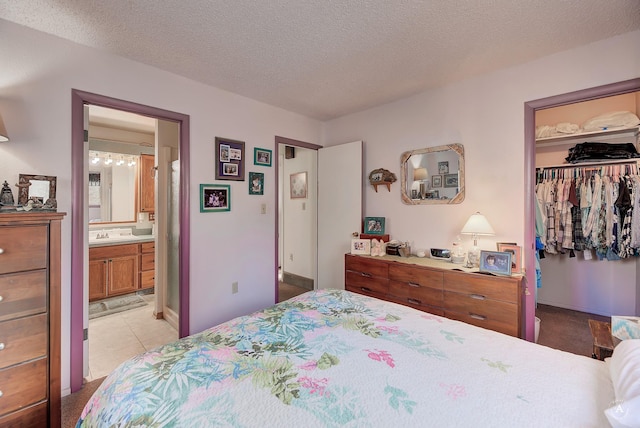 bedroom featuring sink, a textured ceiling, connected bathroom, light tile patterned floors, and a closet