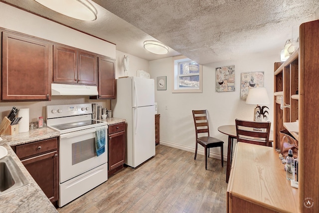 kitchen featuring white appliances, a textured ceiling, light stone counters, and light hardwood / wood-style flooring