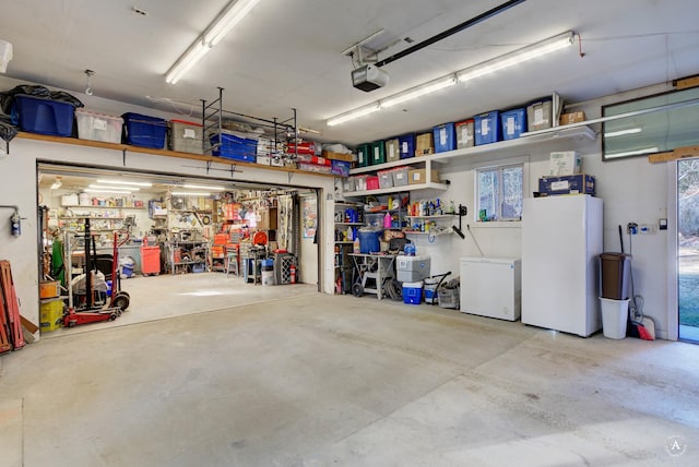 garage with a workshop area, fridge, white fridge, and a garage door opener