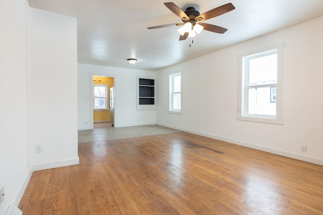 unfurnished room with ceiling fan, plenty of natural light, and wood-type flooring