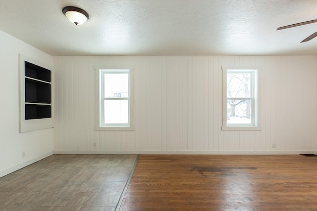 spare room with wooden walls, plenty of natural light, and dark wood-type flooring