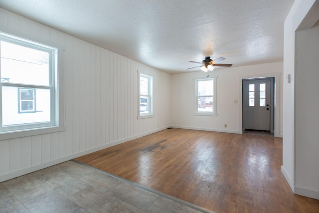 empty room featuring ceiling fan, light wood-type flooring, and a textured ceiling