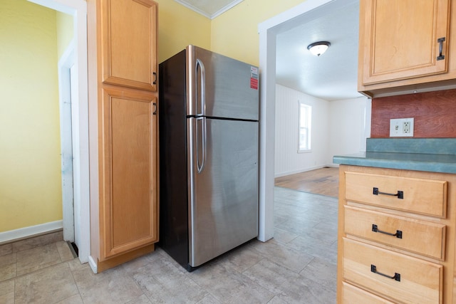 kitchen featuring light brown cabinets, stainless steel refrigerator, and ornamental molding