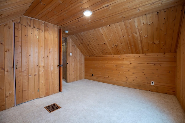 additional living space with light carpet, vaulted ceiling, and wood walls