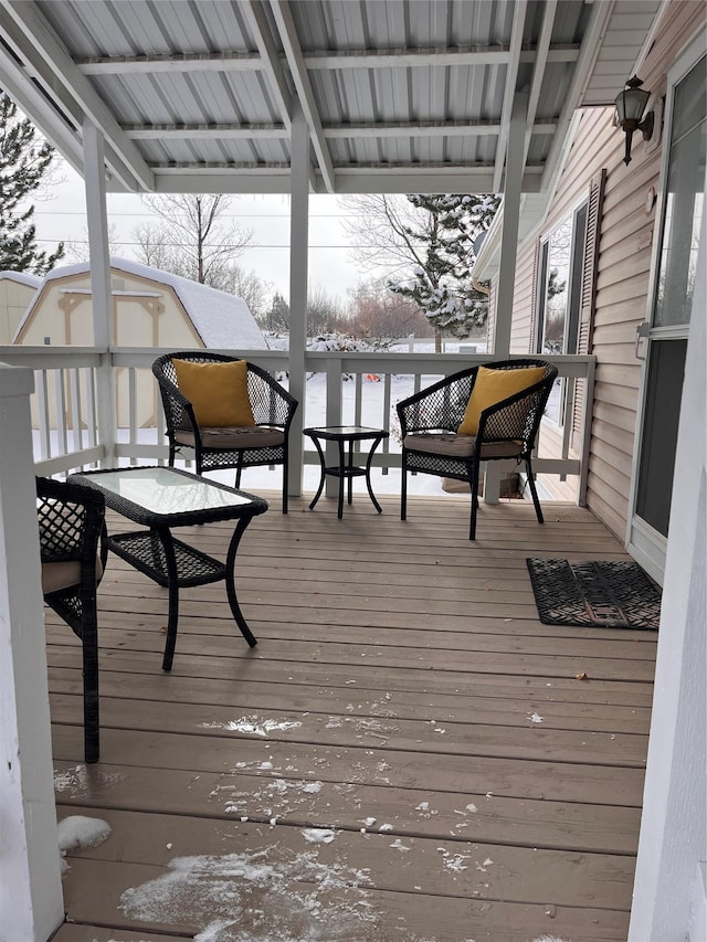 snow covered deck featuring a shed