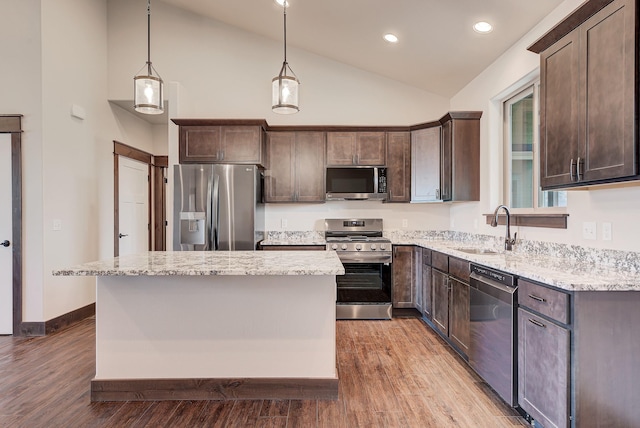 kitchen featuring pendant lighting, stainless steel appliances, a kitchen island, and sink