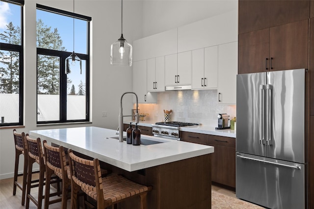 124 W 2nd St Unit B, Whitefish, MT 59937 - kitchen featuring high end refrigerator, range, tasteful backsplash, light countertops, and white cabinets