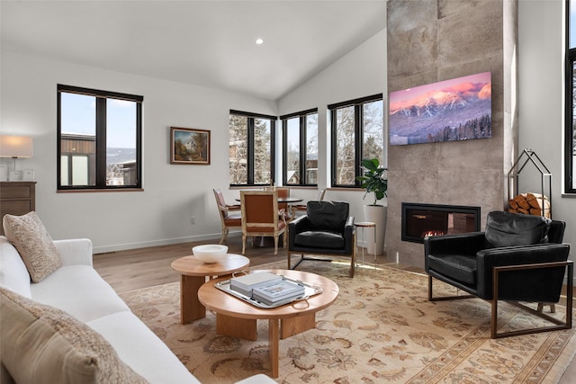 124 W 2nd St Unit B, Whitefish, MT 59937 - living room with lofted ceiling, light wood-type flooring, a tiled fireplace, baseboards, and recessed lighting