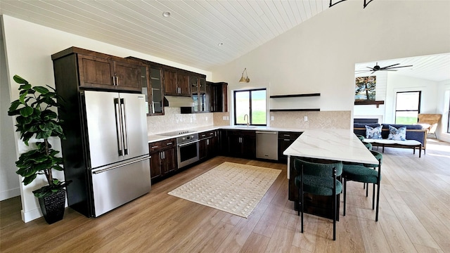 kitchen with light wood finished floors, open shelves, appliances with stainless steel finishes, a sink, and under cabinet range hood