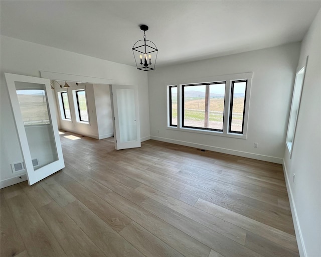 unfurnished dining area featuring an inviting chandelier, plenty of natural light, and wood finished floors