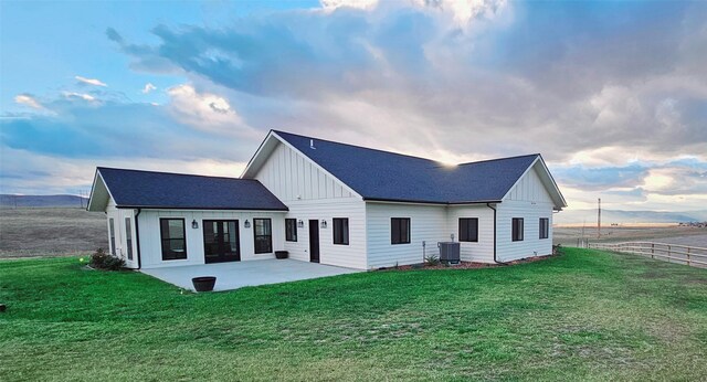 rear view of house featuring a lawn, a patio, and central AC