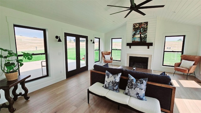 living area with baseboards, vaulted ceiling, french doors, wood-type flooring, and a glass covered fireplace