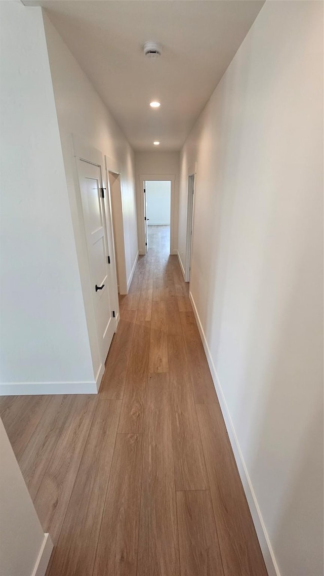 hall with light wood-type flooring and baseboards