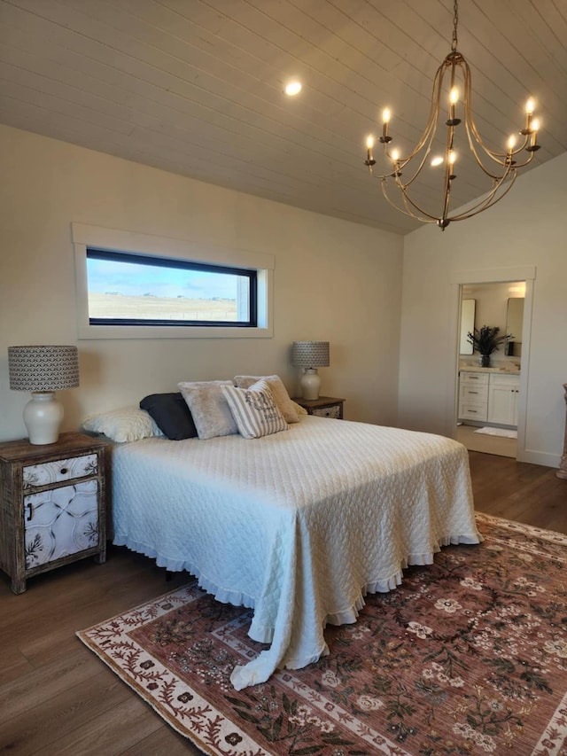 bedroom featuring lofted ceiling, wood finished floors, connected bathroom, and an inviting chandelier