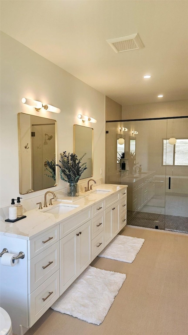 bathroom featuring a stall shower, visible vents, a sink, and double vanity