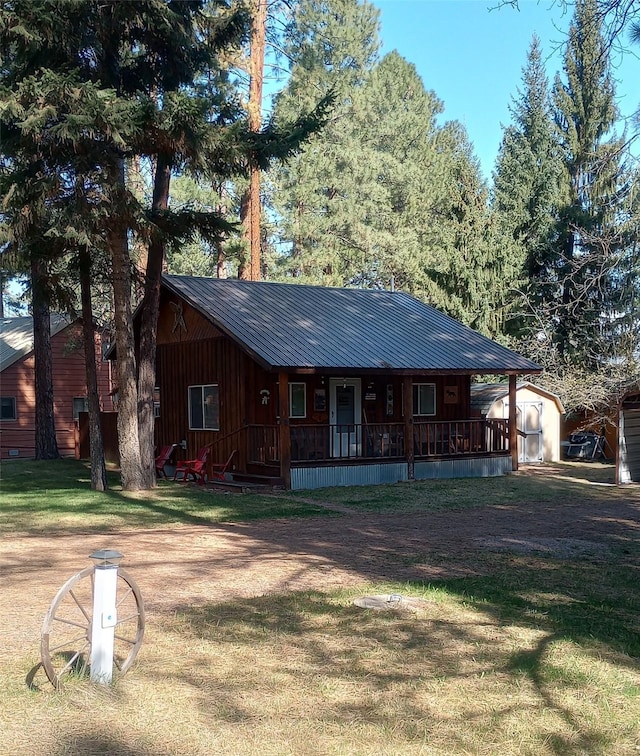 920 N 3rd St, Lincoln, MT 59639 - view of front facade with a front yard, metal roof, a porch, a storage shed, and an outbuilding