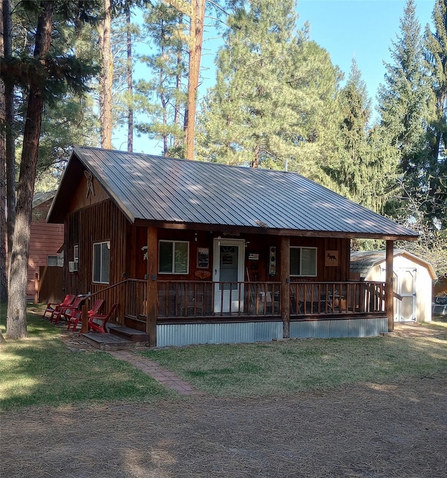 920 N 3rd St, Lincoln, MT 59639 - view of front facade with covered porch, metal roof, a front yard, a storage shed, and an outdoor structure