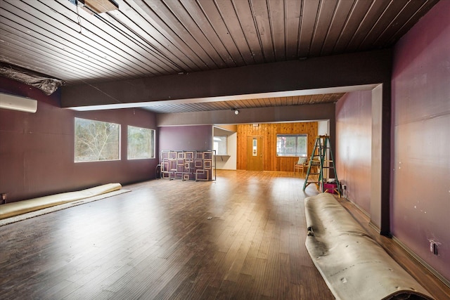 unfurnished living room with beamed ceiling, hardwood / wood-style floors, an AC wall unit, and wooden walls