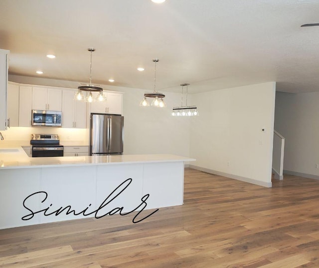 kitchen featuring stainless steel appliances, sink, decorative light fixtures, white cabinets, and light hardwood / wood-style floors