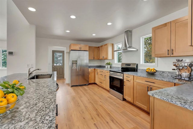 kitchen featuring sink, wall chimney exhaust hood, light brown cabinets, light hardwood / wood-style flooring, and appliances with stainless steel finishes