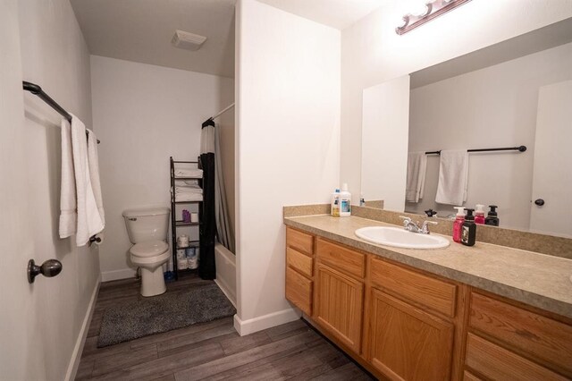 full bathroom with hardwood / wood-style flooring, vanity, toilet, and shower / tub combo