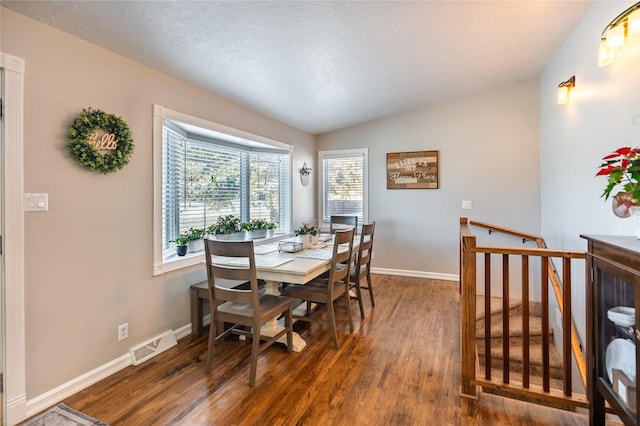 dining room featuring a textured ceiling, dark hardwood / wood-style floors, and vaulted ceiling