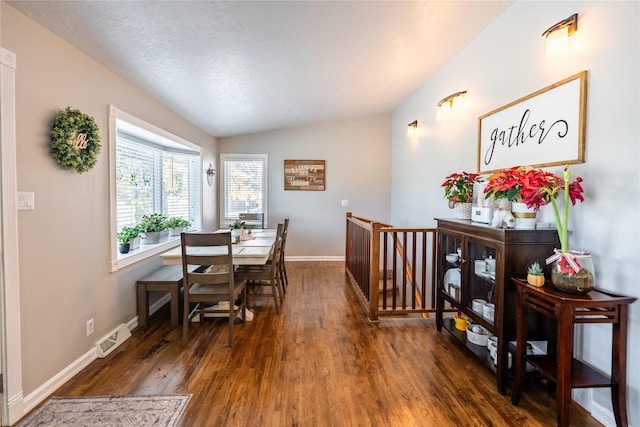 dining room featuring a textured ceiling, dark hardwood / wood-style floors, and vaulted ceiling