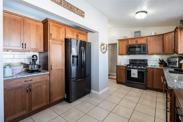 kitchen with stainless steel fridge, light stone counters, range, and backsplash