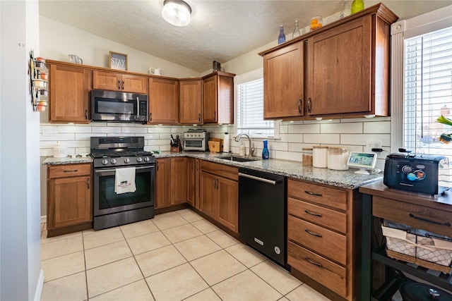 kitchen featuring sink, stainless steel appliances, lofted ceiling, and stone countertops