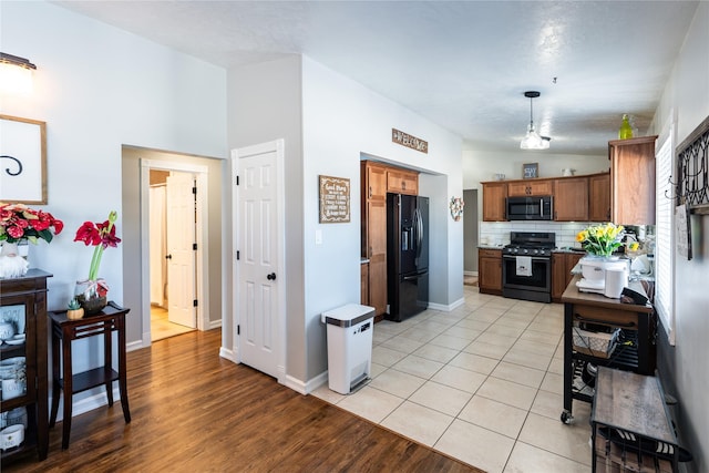 kitchen featuring decorative backsplash, pendant lighting, light tile patterned flooring, and black appliances