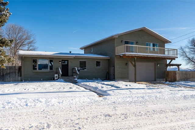 snow covered house with a garage and a balcony