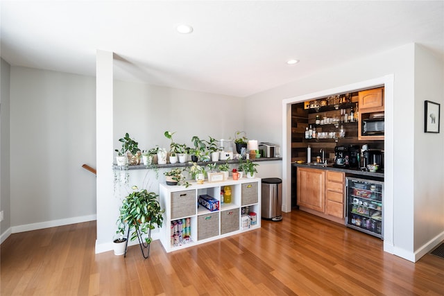 bar with sink, light hardwood / wood-style floors, wine cooler, and black microwave