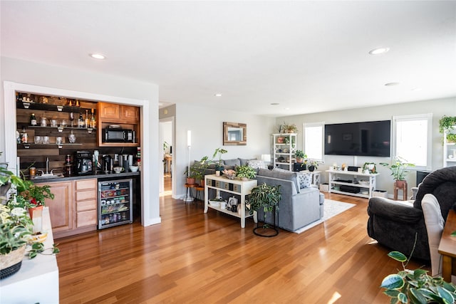 living room featuring light hardwood / wood-style flooring, beverage cooler, and indoor wet bar