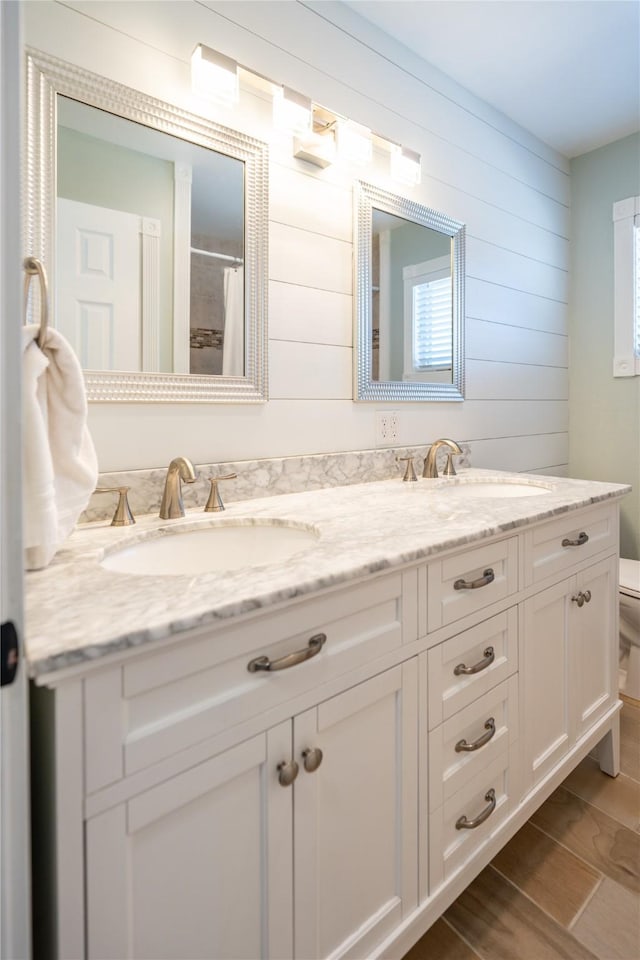 bathroom featuring wood walls, vanity, and toilet