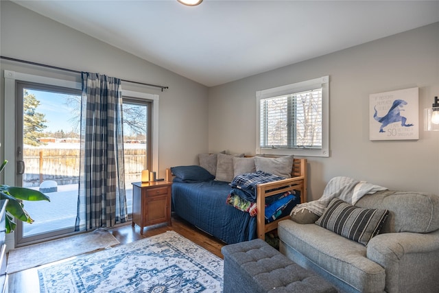 bedroom featuring hardwood / wood-style flooring, lofted ceiling, access to outside, and multiple windows