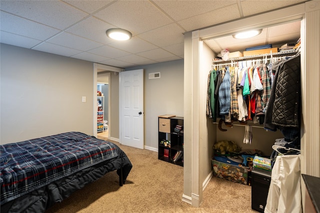 bedroom with carpet flooring, a drop ceiling, and a closet