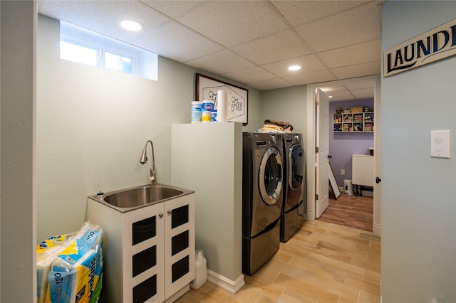 clothes washing area featuring light hardwood / wood-style floors, sink, and washing machine and clothes dryer