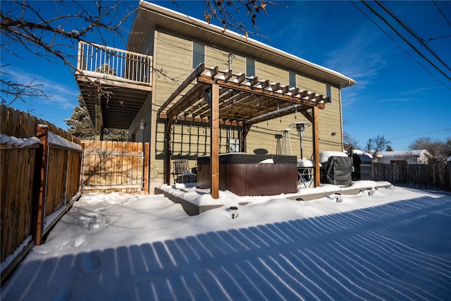 snow covered patio with a pergola, a balcony, and a hot tub