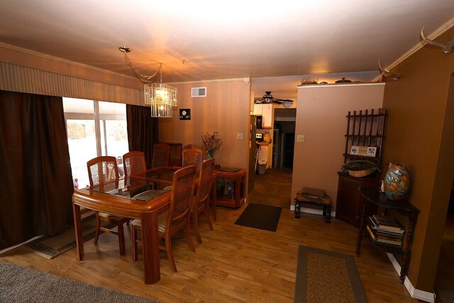 dining room featuring ornamental molding, ceiling fan with notable chandelier, light wood-type flooring, and visible vents