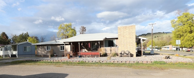 view of front of property with covered porch, a chimney, and metal roof
