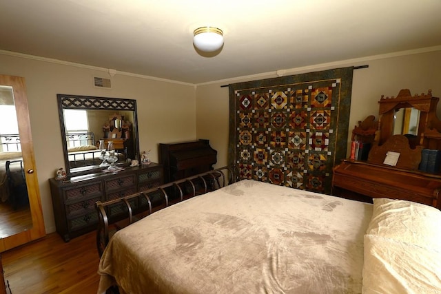 bedroom with visible vents, ornamental molding, and wood finished floors